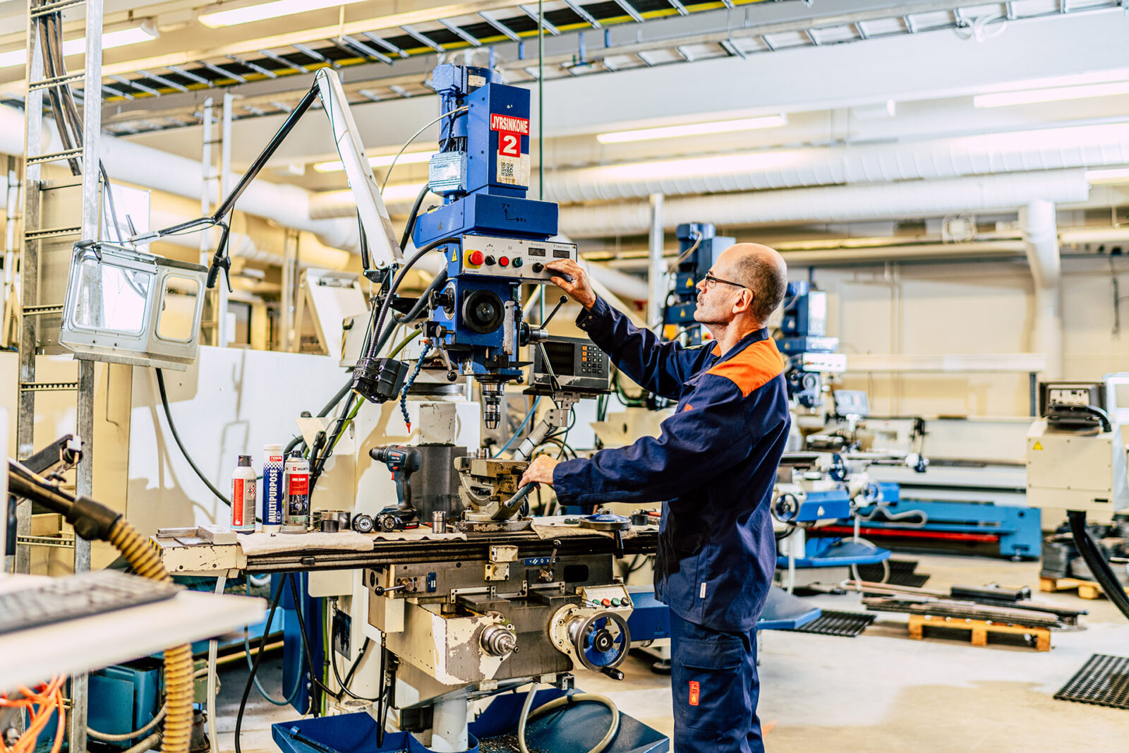 mies käyttää jyrsinkonetta metallialan työhallissa